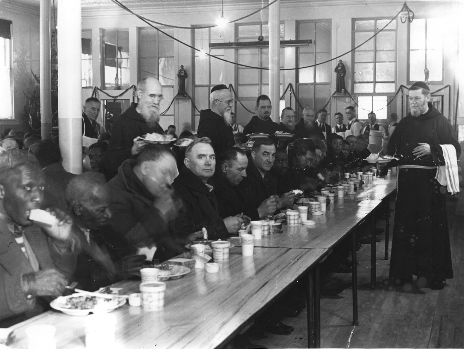 Blessed Solanus Casey is pictured among the friars and volunteers serving guests in this undated photo. The Capuchin Soup Kitchen was founded by Fr. Herman Buss, OFM Cap., who served as the kitchen's first director. (Photo courtesy of the Capuchin Franciscan Province of St. Joseph)