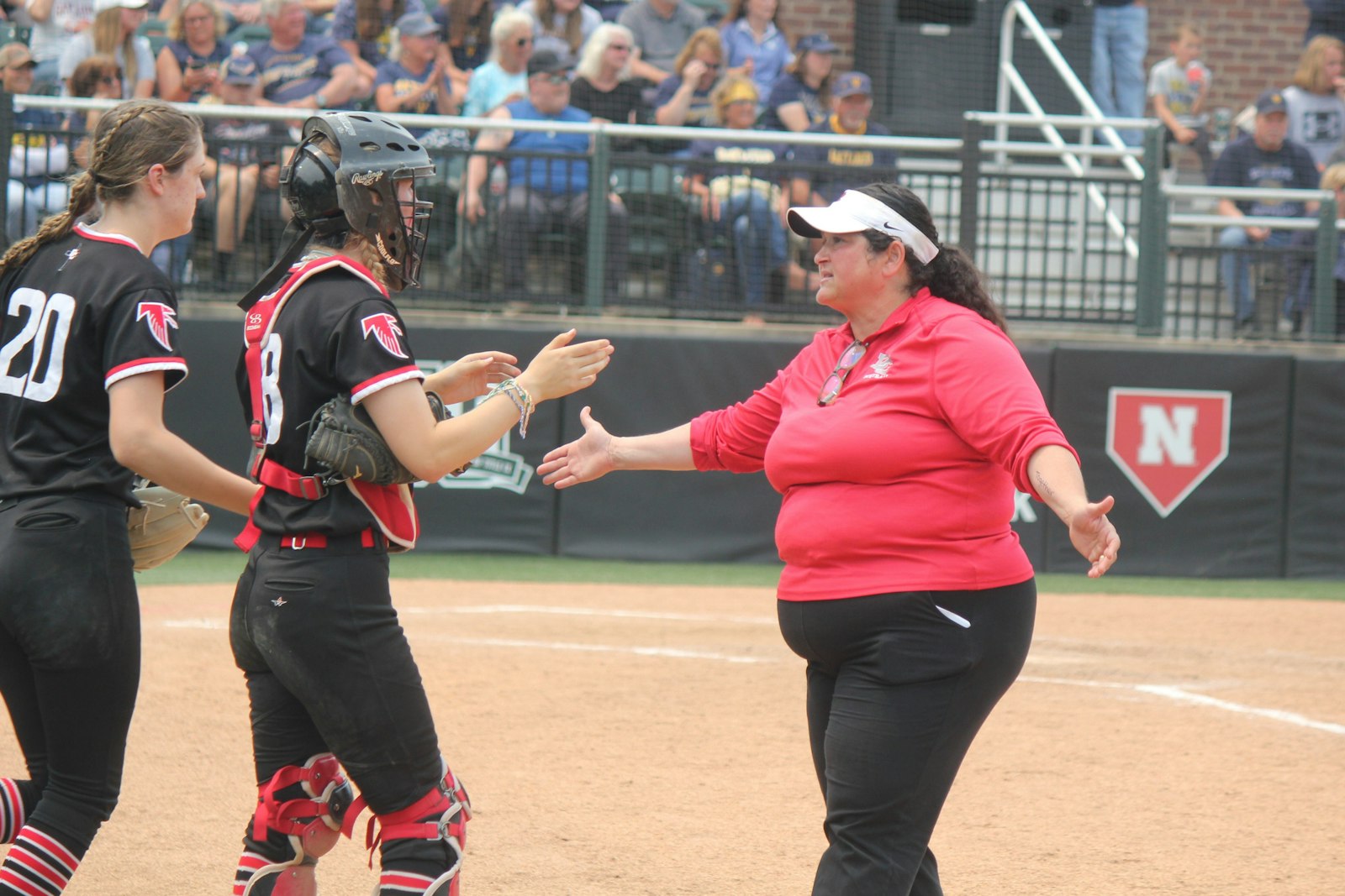 Head coach Regina Dunn congratulates pitcher Jess Nelson and catcher Madison Mosier after getting out of a fifth-inning jam.