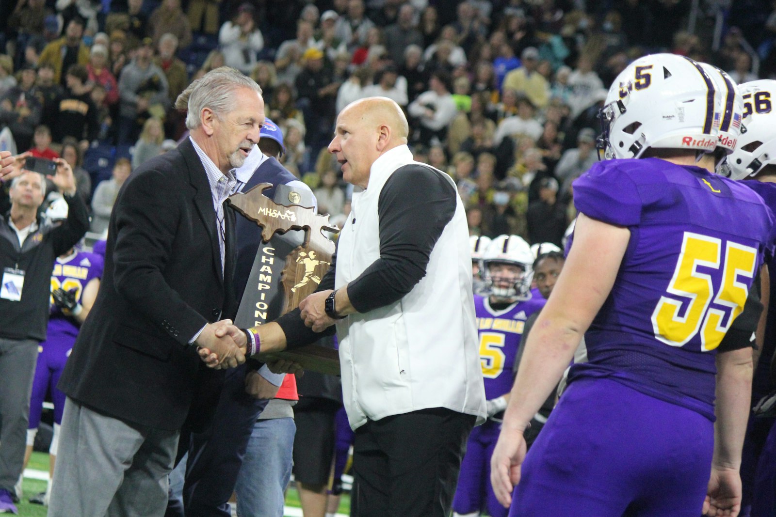 Catholic League Director Vic Michaels presents Warren De La Salle head coach and athletic director Dan Rohn with the state championship trophy – the fourth one to be claimed by the Pilots in the past decade.