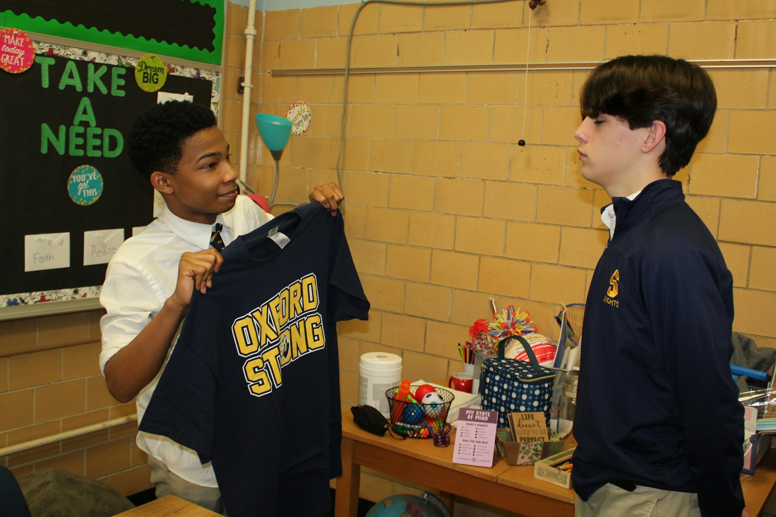 Royal Oak Shrine Catholic High School freshman Cordell Walton shows off a newly delivered Oxford Strong t-shirt to classmate Maxwell Dorian. Shrine students are encouraged to wear their shirts Feb. 4 when the school hosts a girls basketball game against Allen Park Cabrini. (Photo by Wright Wilson | Special to Detroit Catholic)