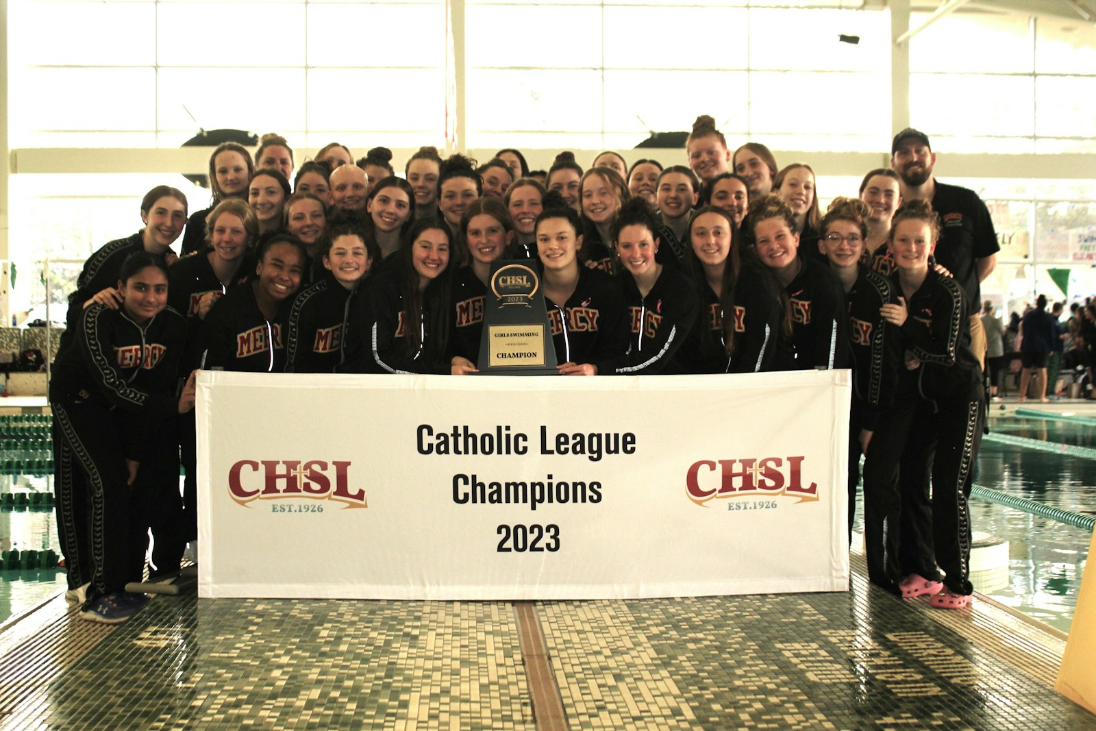 This is a familiar sight at the Catholic League swimming and diving championship meet: Farmington Hills Mercy posing with the first-place trophy.