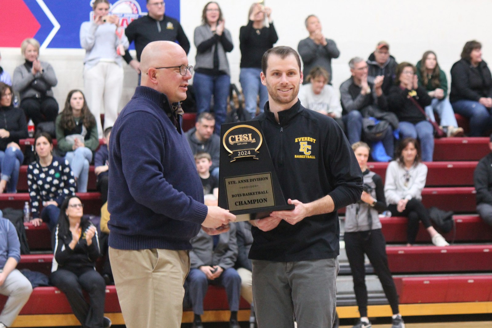 Catholic High School League associate director Mike Evoy presents the St. Anne’s Division championship trophy to Everest head coach Rich Cross. The Mountaineers defeated Waterford Our Lady of the Lakes, 49-29.