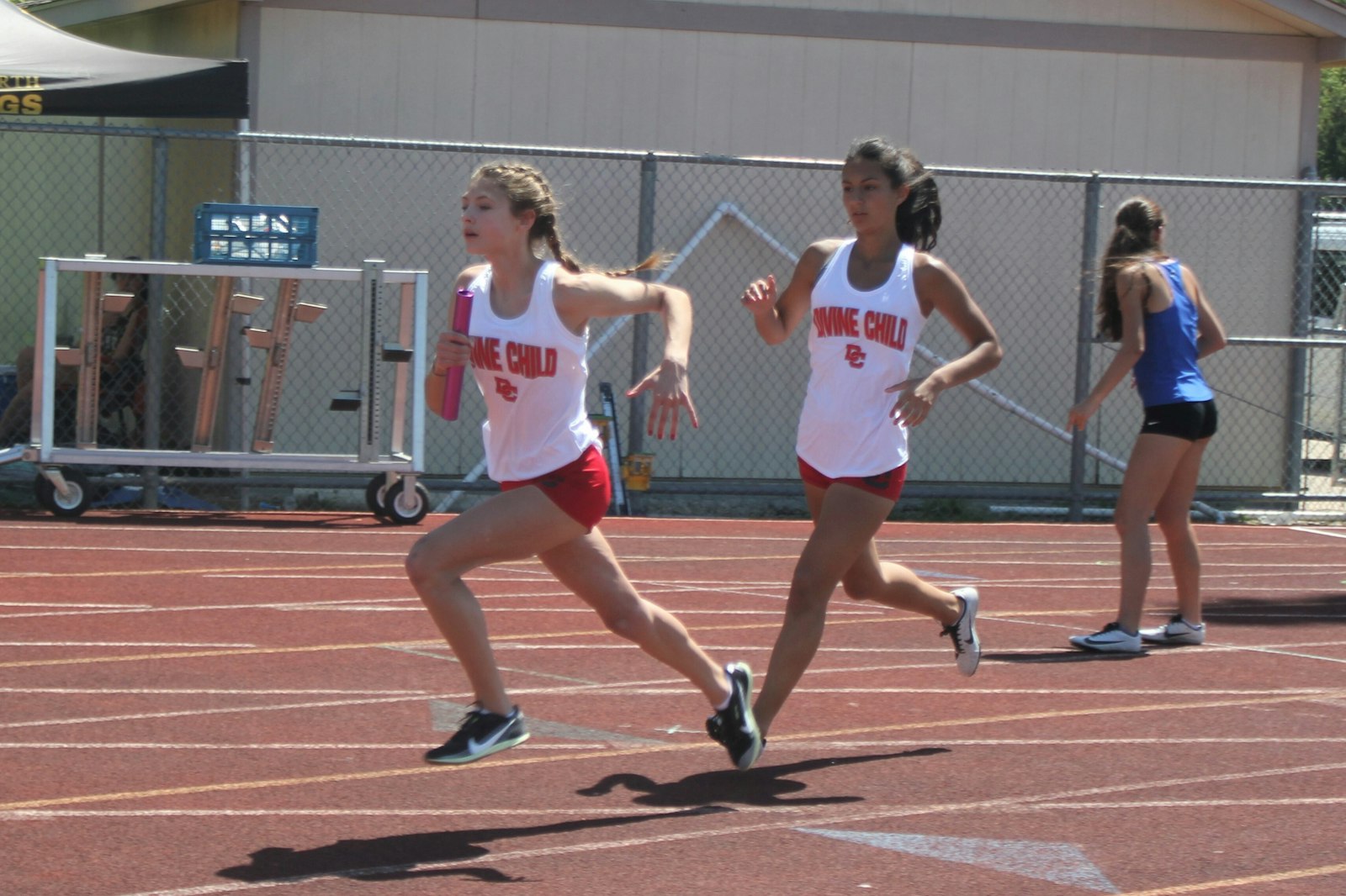 Divine Child’s Katie Kurtinaitis takes the baton from teammate Olivia Vazquez at the midway point of the 4x200 relay. The Falcons won the race, and their three victorious relay teams helped them win the Catholic League Bishop Division track team title.