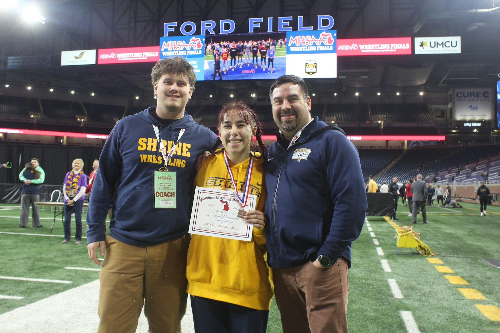 Royal Oak Shrine’s Katrina Shammami became her school’s first all-state wrestler by finishing third in the 155-pound weight class. She celebrates with assistant coach Nick Di Giovanni and head coach Bob Losey.