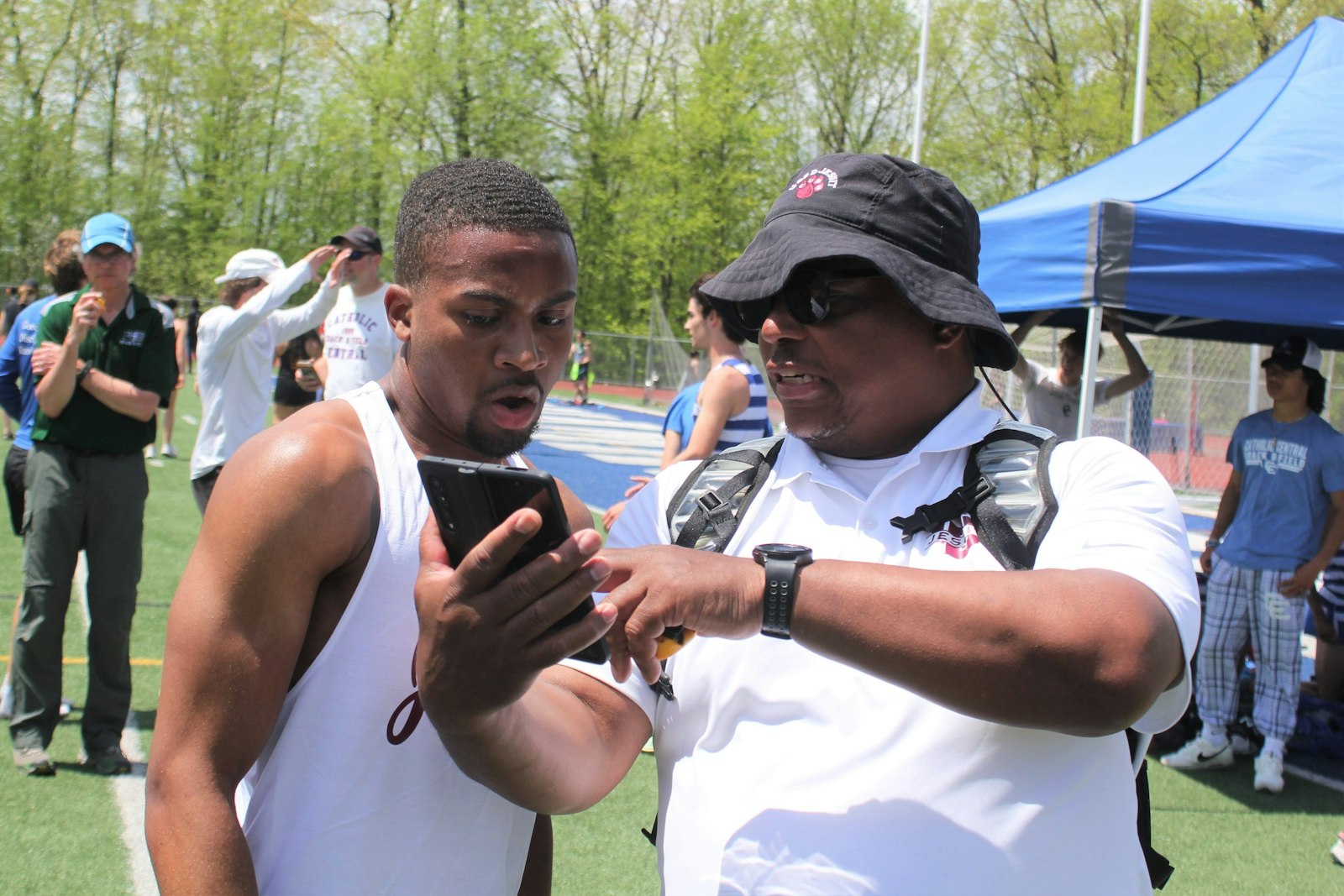 University of Detroit Jesuit coach Carl Brock shows his stopwatch to senior Kamari Tensley, verifying that Tensley broke two minutes in the 800-meter run for the first time (1:59.65).