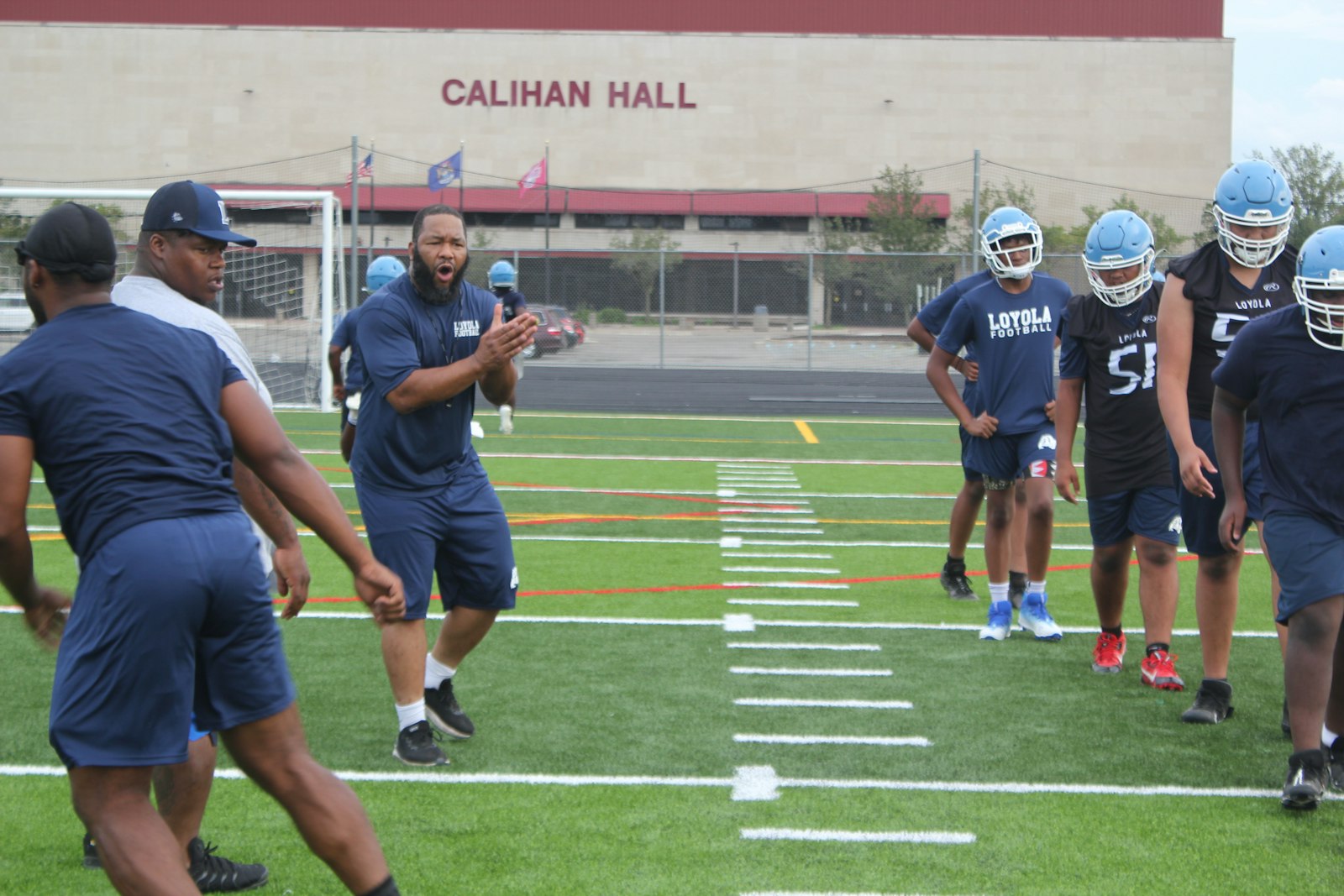 In the shadow of Calihan Hall, Loyola High School coach Terrance Sims encourages his players during a drill.