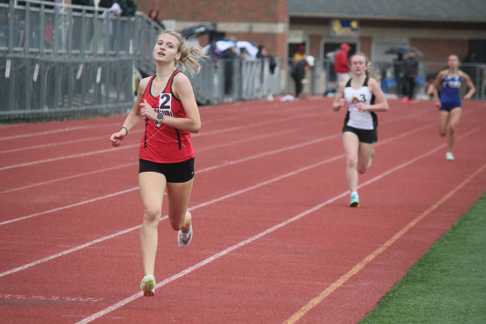 Dearborn Divine Child’s Kirsten Koss glances at the clock right before crossing the finish line in front of the other 800-meter run competitors. Koss’ winning time was a personal-best 2:19.82 as the Falcons won six events Saturday at Catholic Central.