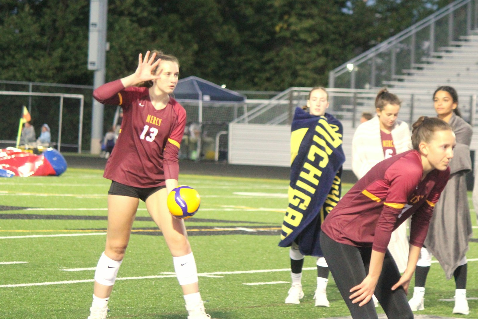 While her Mercy teammates shivered on the sideline, Ella Andrews gets ready to serve the ball early in the match.