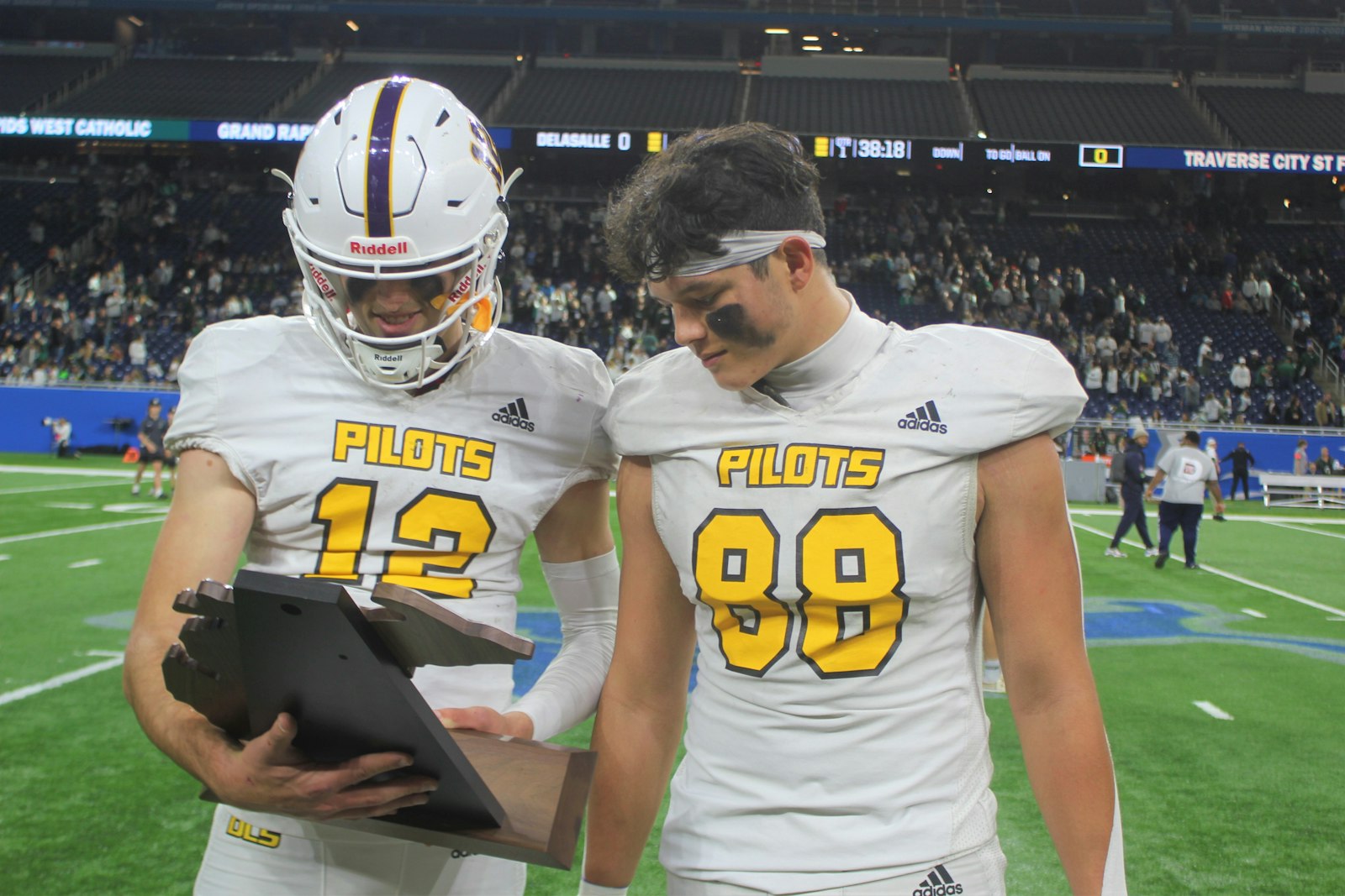 Captains Brady Drogosh and Mason Muragin admire the trophy the Warren DeLaSalle Pilots received for winning the Division 2 state football championship.
