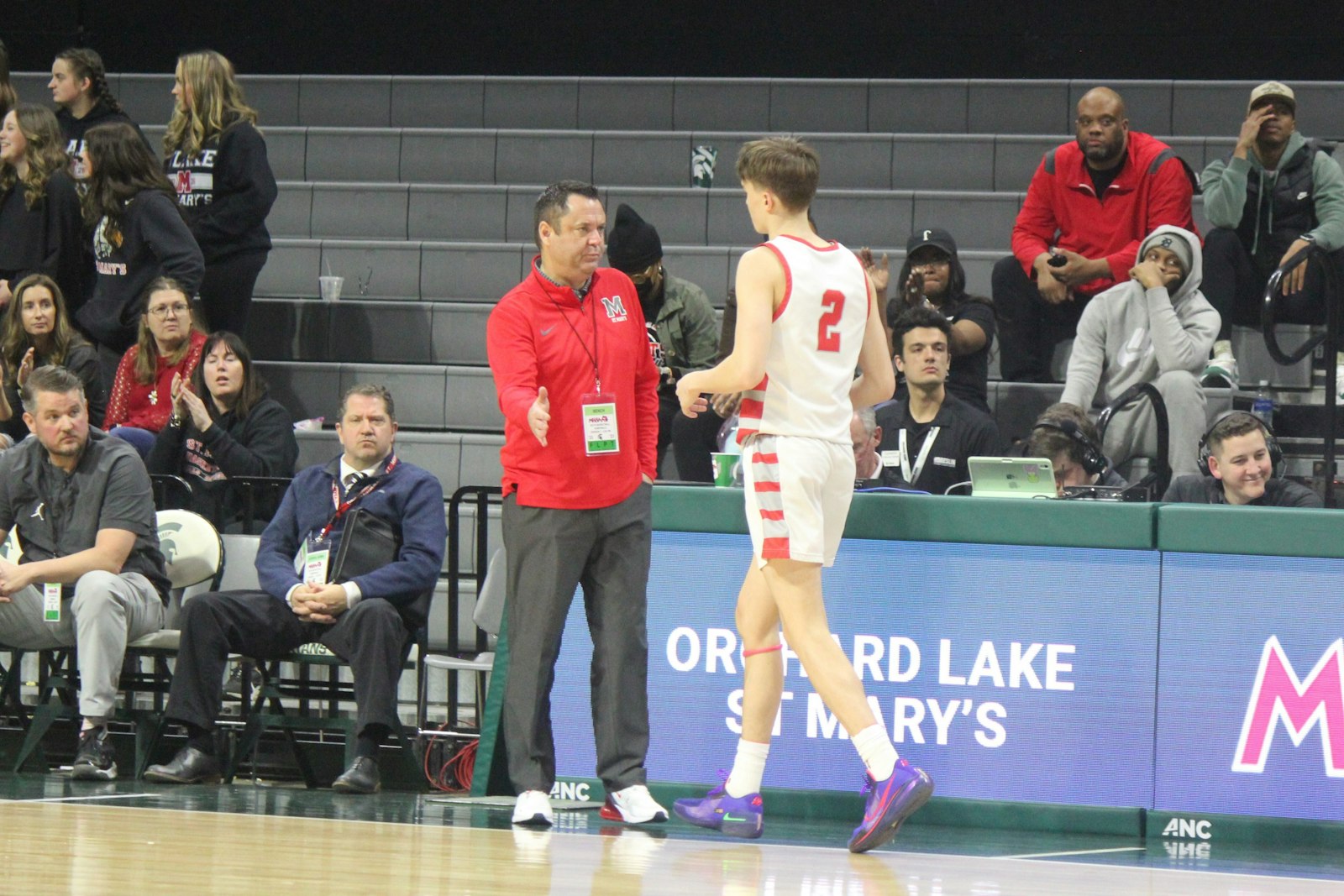 St. Mary’s coach Todd Covert congratulates junior guard Daniel Smythe for his efforts after leaving the court during the fourth quarter in the Eaglets’ loss to Muskegon in the state semi-finals.