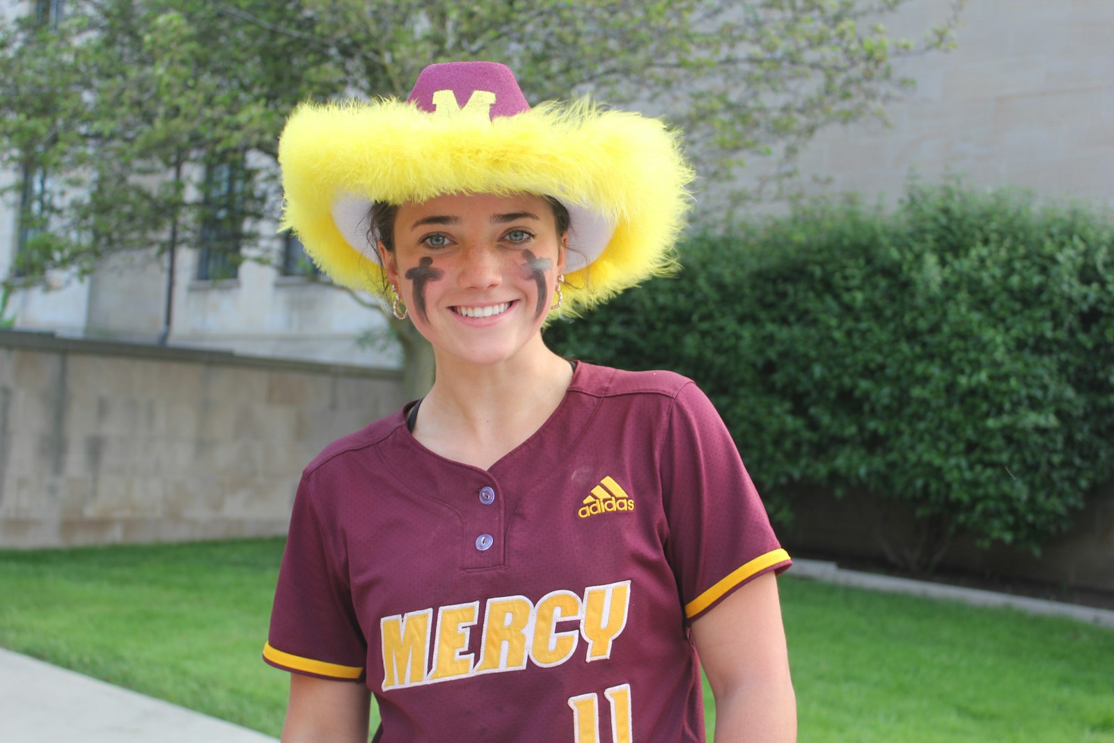 Senior shortstop Gage Lambert shows off her prize for getting the game-winning hit: a fringed maroon-and-gold cowboy hat, passed around among the Mercy team to the player who makes the clutch play.