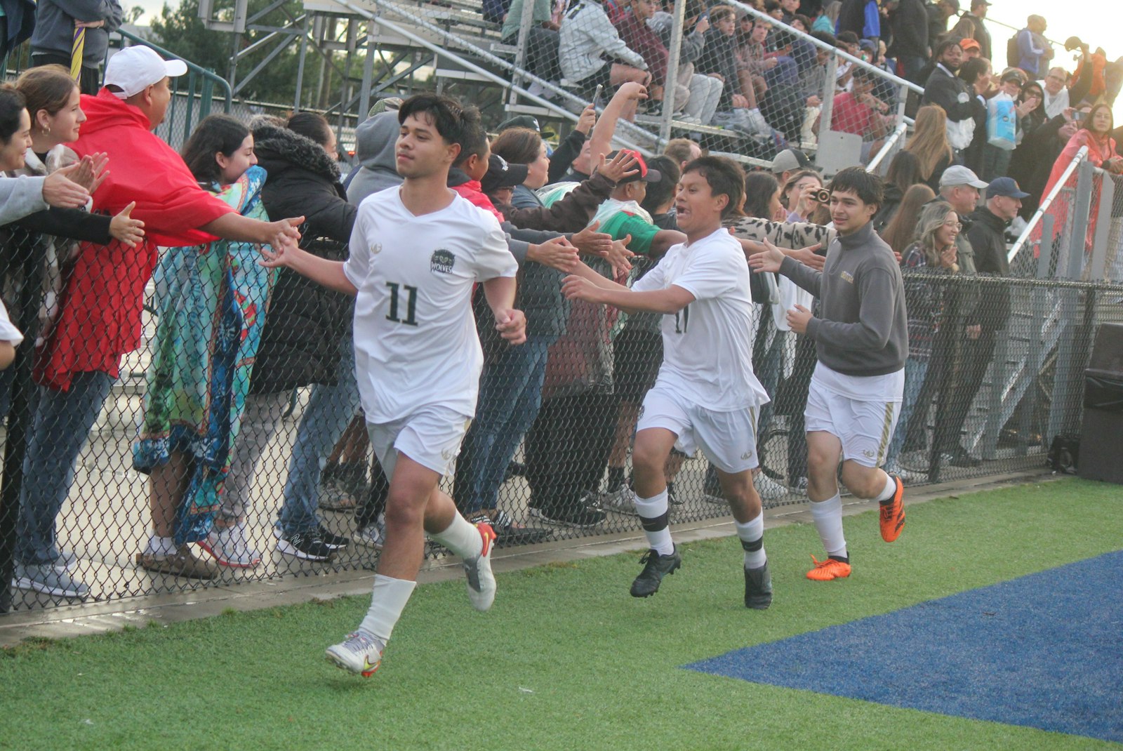 Hugo Romero leads the team procession after the game past excited Detroit Cristo Rey fans lining the sideline fence. The Wolves’ 2-0 victory earned them their first Catholic High School League championship in school history, in any sport.