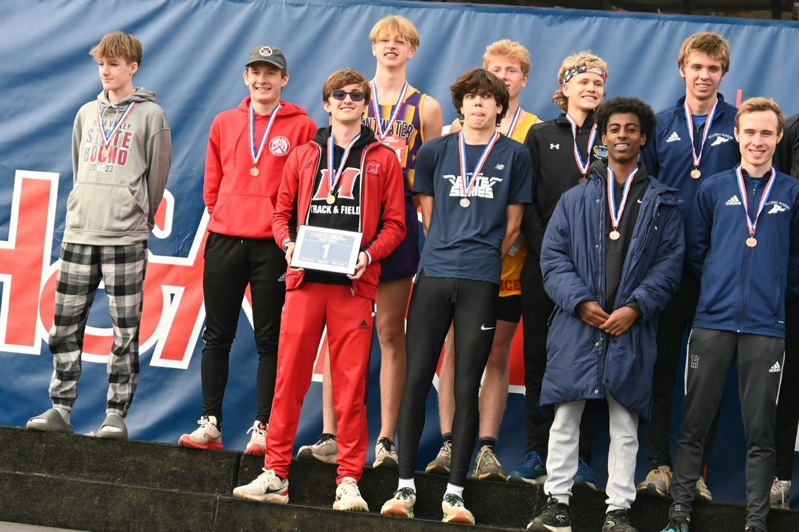 Holding the coveted No. 1 sign, Marine City Cardinal Mooney senior Tyler Lenn receives accolades on the awards stand after winning the Division 4 cross-country state title. Two places to the right is Abenezer Cerone of Royal Oak Shrine, who finished third. (Fred Huysentruyt | Special to Detroit Catholic)