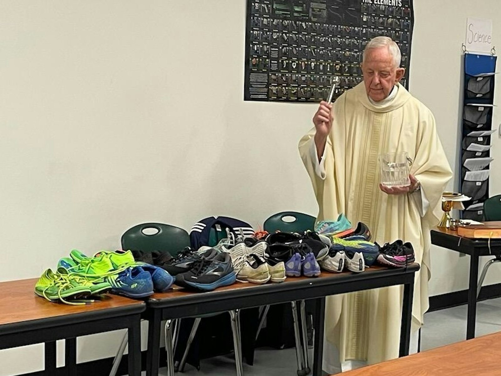 Fr. Joseph Lang prepares to bless the running shoes of the Royal Oak Shrine cross-country runners during a special team mass held in advance of the state championship meet. (Courtesy of Faith Luddy)